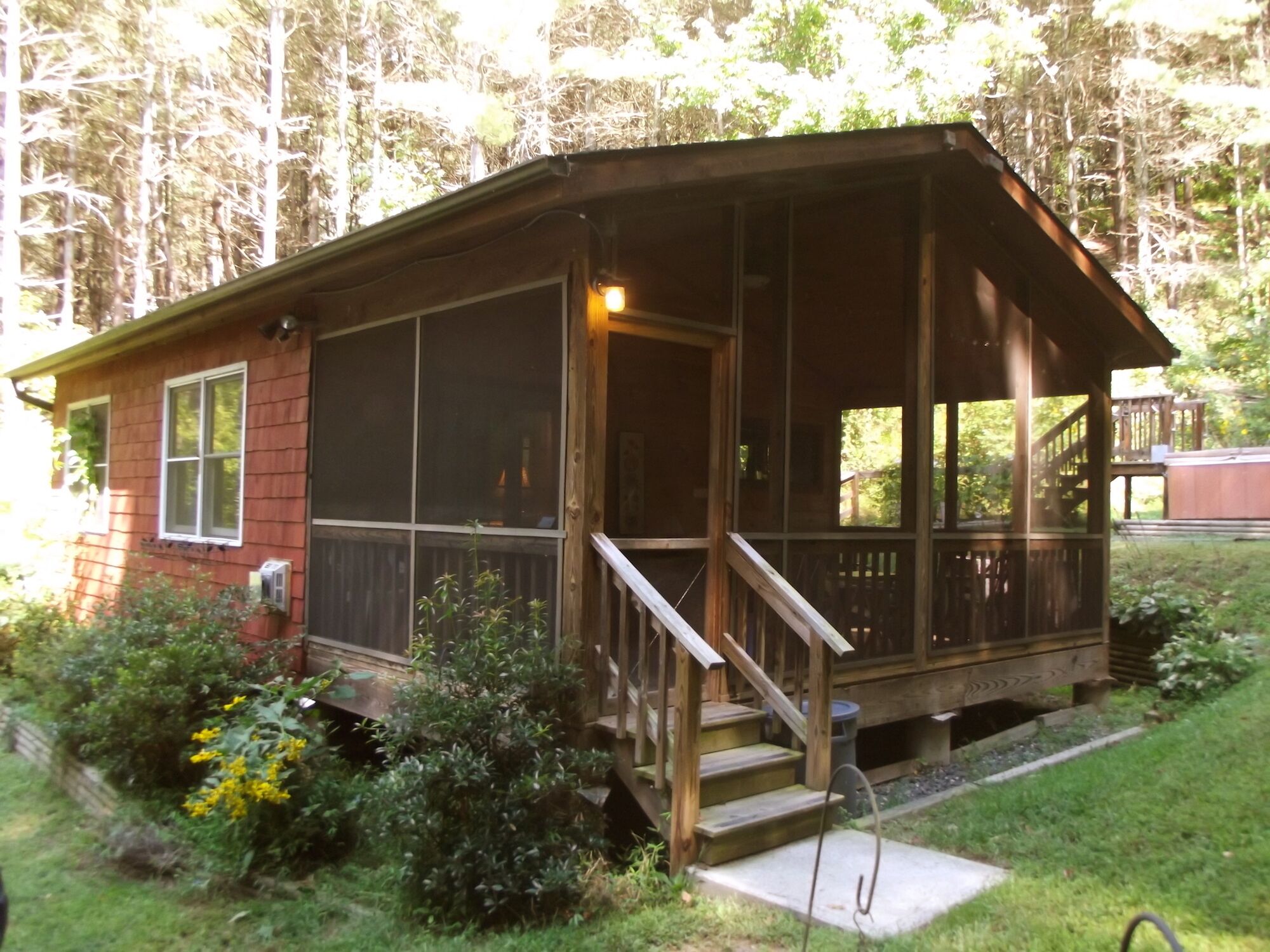 A wooden cabin with a porch, a staircase, and a window.