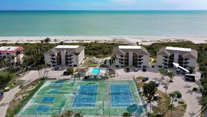 A beachfront hotel with multiple tennis courts, a swimming pool, and a parking area. - Sanddollar #A202 is a 3/2 beachfront Vacation Rental on Sanibel Island (Sanibel)