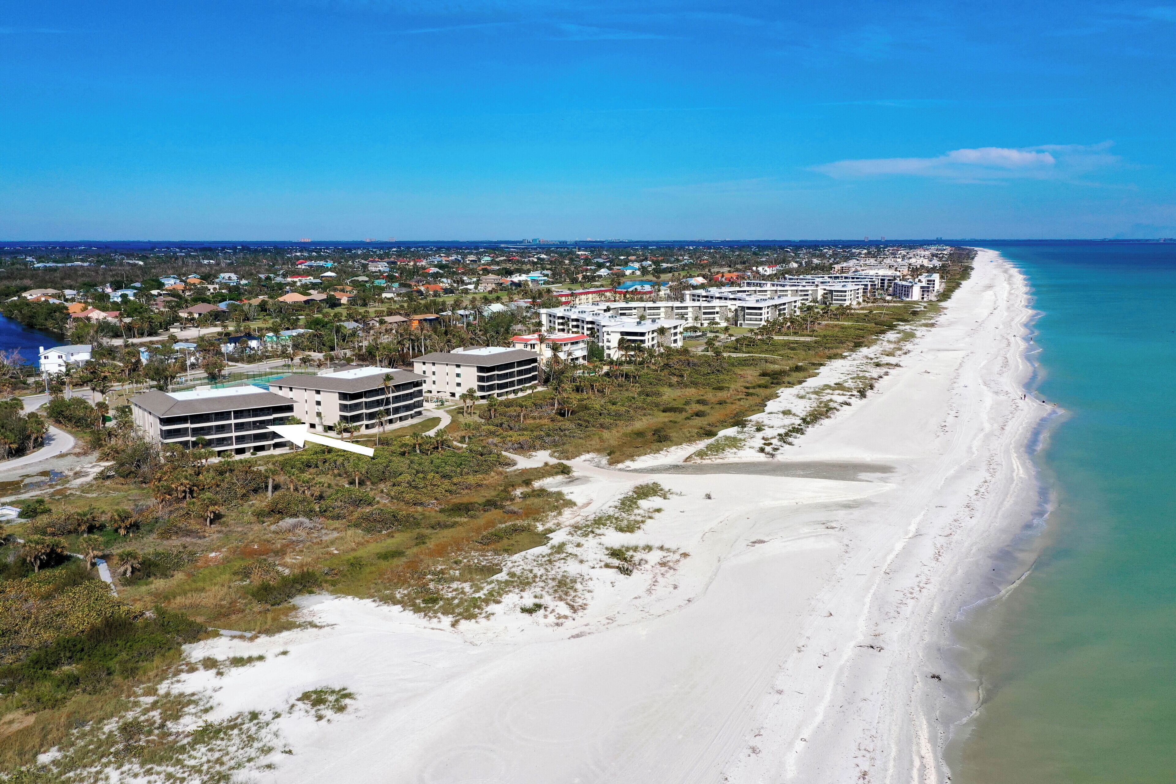 Ein Küstenhotel mit mehreren Gebäuden, einem Sandstrand und freiem Blick auf den Ozean.