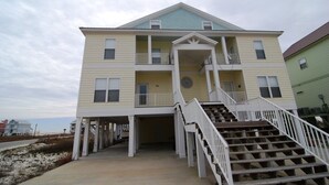 A two-story building with a balcony on the second floor, a covered entrance, and a staircase leading to the main entrance. - 5BR Fort Morgan Gulf View Duplex (GULF SHORES)