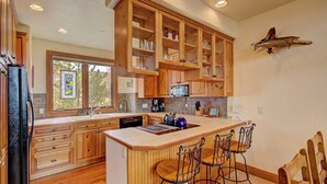 Une cuisine moderne avec des meubles en bois, une grande fenêtre et un coin bar avec des tabourets.