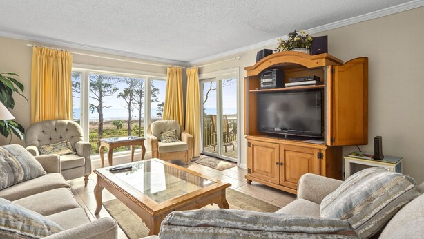 A spacious living room with a large TV, comfortable seating, and a view of the outdoors.