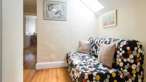A cozy room with a wooden floor, a colorful sofa, and a skylight. - Salem 3rd floor 3BR Apartment (Salem)