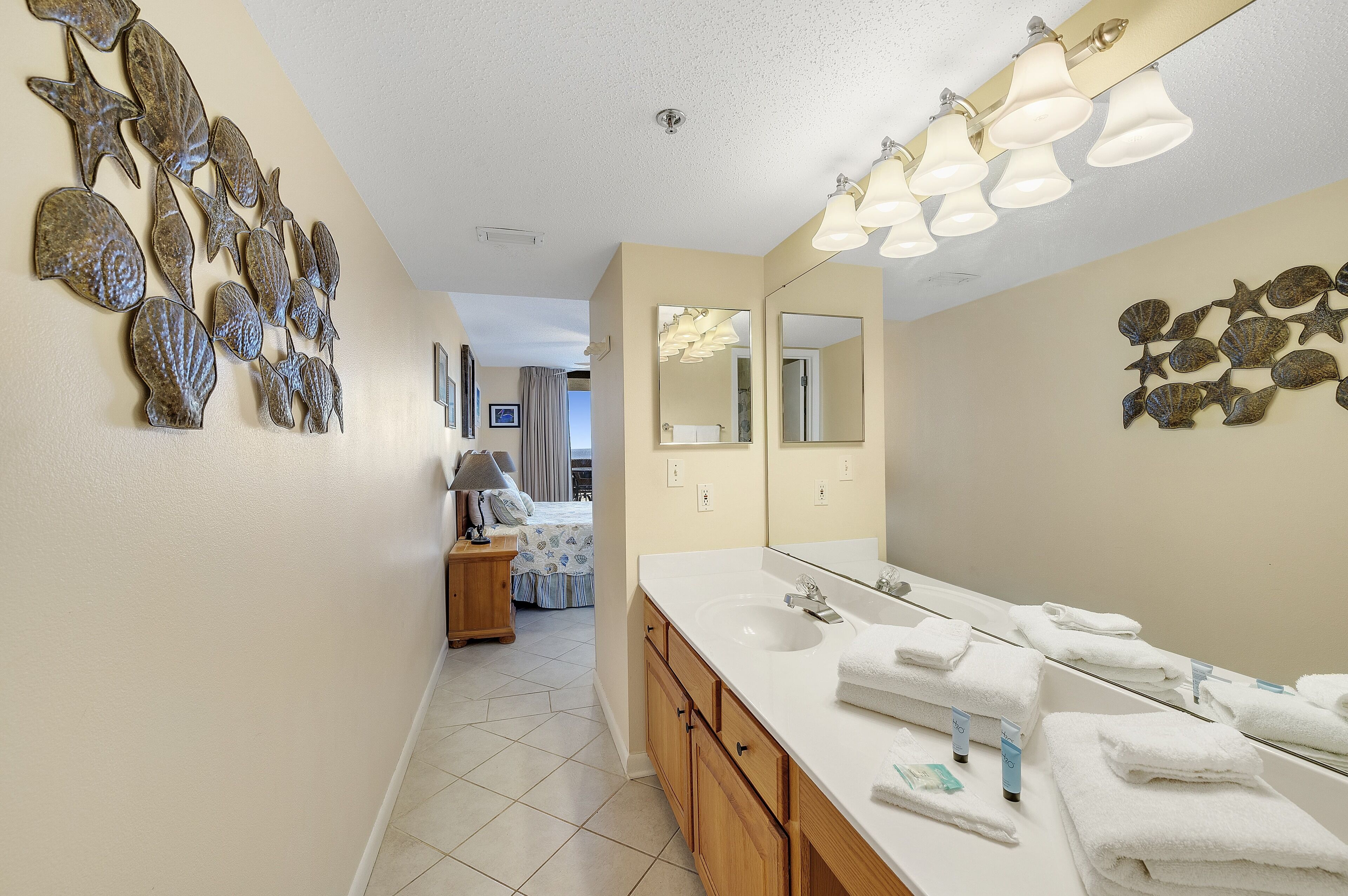 A bathroom with a large mirror, multiple sinks, and decorative shells on the walls.