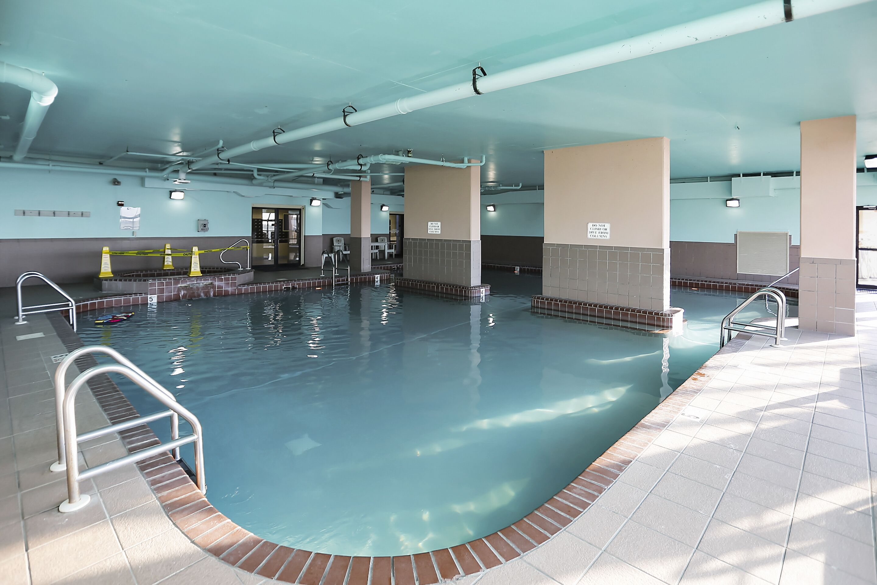 Une piscine intérieure à l’eau claire, avec des murs et un sol carrelés.