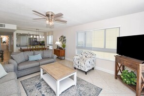 A living room with a sofa, coffee table, TV stand, and a ceiling fan.