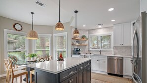 A modern kitchen with a central island, white cabinetry, and a stainless steel refrigerator.