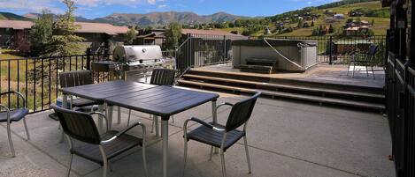 Un patio exterior con mesa y sillas, una parrilla y vistas a un paisaje montañoso.