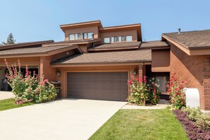 A modern two-story house with a garage, a covered patio, and a well-maintained lawn.