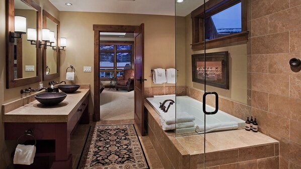 A modern bathroom with a large mirror, two sinks, a bathtub, and a shower.