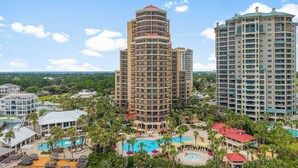 A high-rise hotel with multiple balconies, a central pool area, and surrounding greenery. - Beachfront ~ Spacious Kitchen ~ Private Balcony (Miramar Beach)