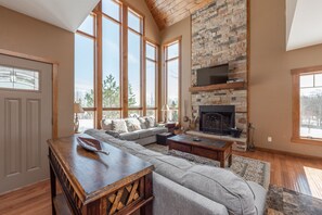 A spacious living room with a large sectional sofa, a fireplace, and large windows. - Views, Trails & Luxury w/ Hot Tub & Fire Pit (McHenry)