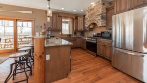Una cocina amplia con armarios de madera, una isla central y una chimenea de piedra.