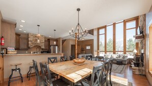 Una cocina amplia con una gran mesa de madera, electrodomésticos modernos y amplios ventanales que dejan entrar mucha luz natural.