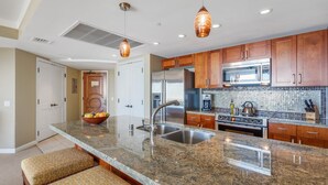 A modern kitchen with granite countertops, stainless steel appliances, and wooden cabinets. - Maui Resort Rentals:  Honua Kai Konea 933 – 2 BR Corner w/ Sweeping 9th Floor Ocean and Black Rock Views! (Lahaina)
