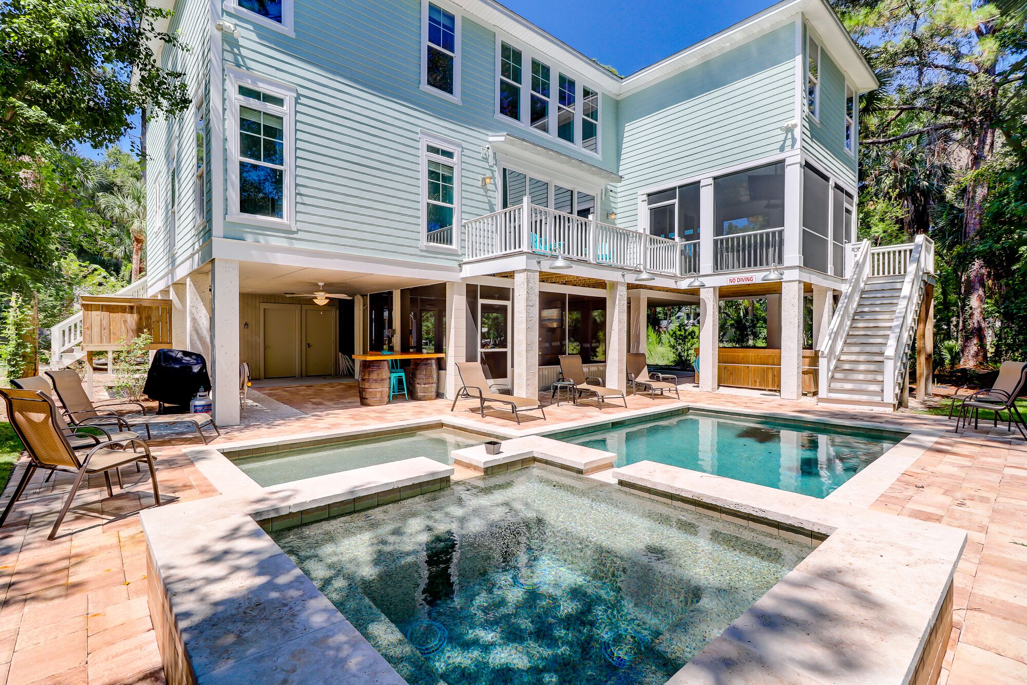 A two-story house with a pool area, outdoor seating, and a covered patio.
