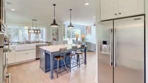 A modern kitchen with a central island, bar stools, stainless steel appliances, and pendant lighting. - 3B Hickory Lane-CUSTOM built house!  200 Yards till your feet are in the sand (Hilton Head Island)