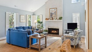 A living room with a fireplace, a sofa, a chair, and a television. - 47 S. Beach Ln | 4 Bedroom 5th Row Ocean | Pet Friendly | STR #029802 (Hilton Head Island)