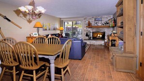 A cozy living room with a fireplace, wooden furniture, and a dining area. - The Bluebell, Chateaux Condo, Pool, Hot tub, Sauna (Mt. Crested Butte)