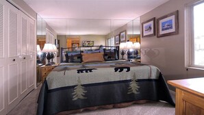 A bedroom with a bed, two bedside lamps, a dresser, a mirror, and a window. - The Bluebell, Chateaux Condo, Pool, Hot tub, Sauna (Mt. Crested Butte)