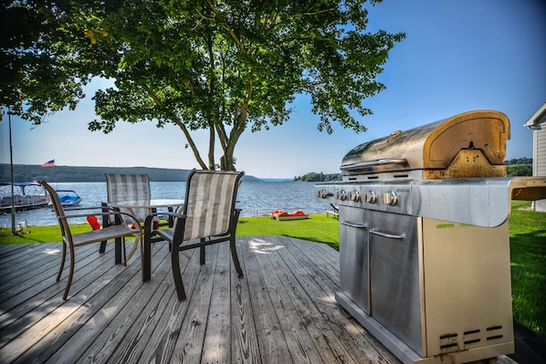 A deck with a grill, chairs, and a view of a lake. - Captain Jacks II: Lakeside tranquility! (Branchport)