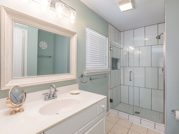 Een badkamer met een wastafel, spiegel en douche.