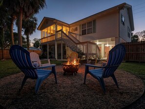A two-story house with a covered deck and a fire pit in the backyard. - The Flying Pigs Cottage | Pet Friendly, Fire Pit! (Tybee Island)