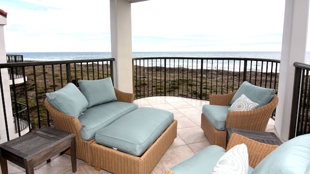 Un balcón con muebles de mimbre y vista al mar.