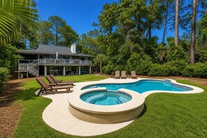 A house with a swimming pool, a deck with lounge chairs, and a staircase leading to a balcony.