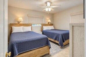 Un dormitorio con dos camas, ventilador de techo y lámparas de pared.