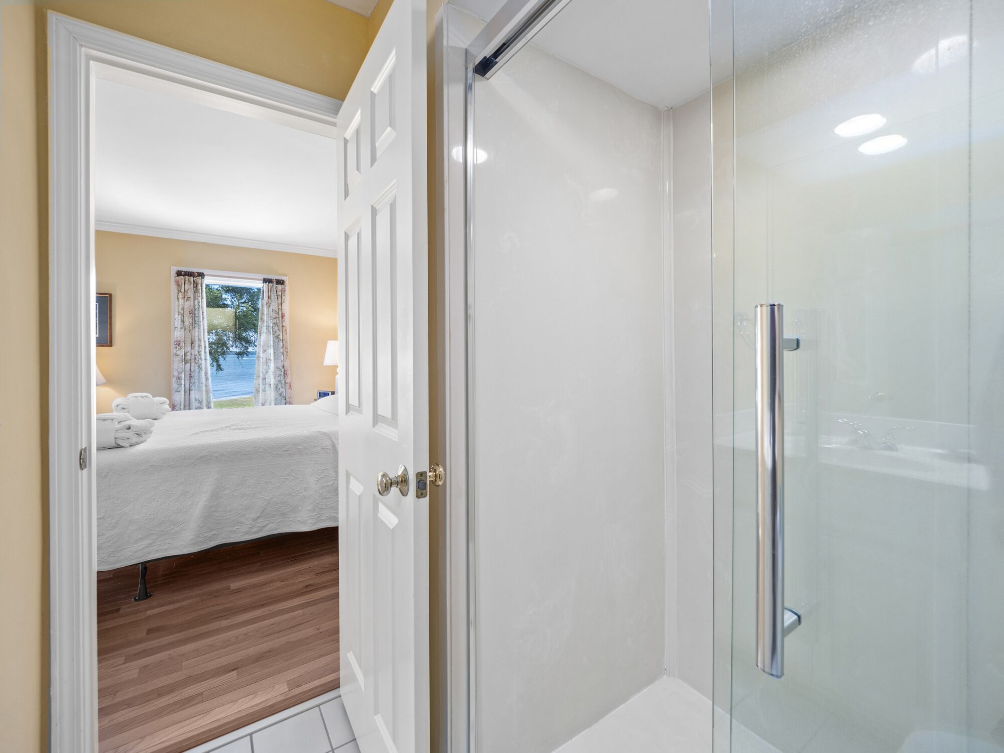 Een hotelkamer met een bed, een badkamer met een douchecabine van glas en uitzicht op de omgeving.