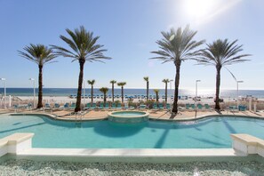 A pool with a view of the beach and palm trees. - Boardwalk Beach Resort Family Getaway with Splash Zone and Gulf Views (Panama City Beach)