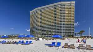 A beachfront hotel with multiple balconies, sun loungers, and umbrellas. - Boardwalk Beach Resort Family Getaway with Splash Zone and Gulf Views (Panama City Beach)