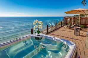 A hot tub with a view of the ocean, a wooden deck, and a lounge area with an umbrella. - Gorgeous Eight Bedroom Oceanfront Home E396-0 (Encinitas)