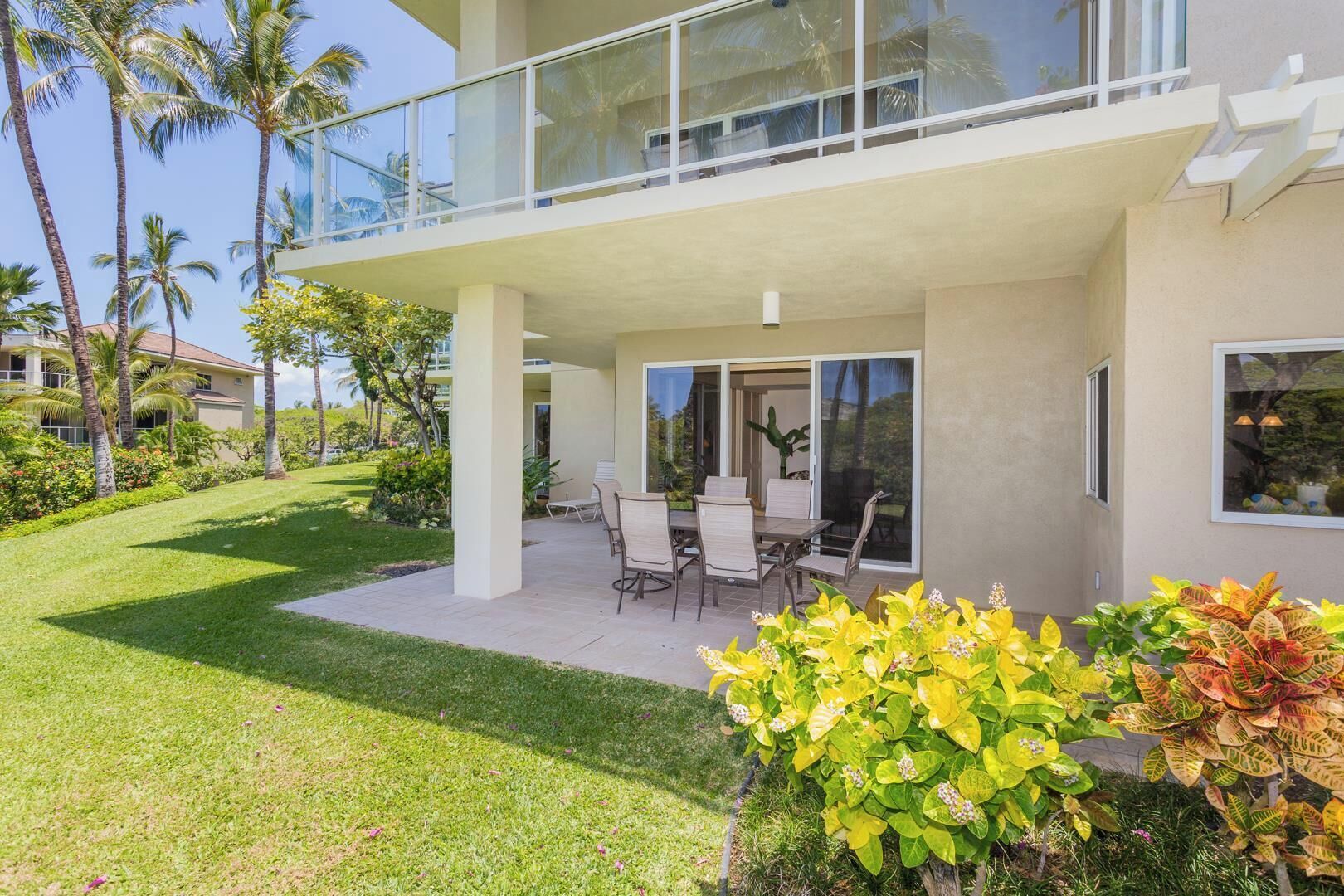 A modern two-story house with a covered patio, outdoor seating, and lush landscaping.