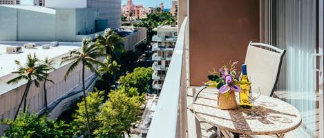 A balcony with a table set for two, featuring a bottle and a glass.