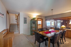 A dining area with a wooden table and chairs, a kitchen in the background, and a view of the outdoors. - Lakefront Northshore Townhome pano lake views, HOA private beach pool tennis (Tahoe City)