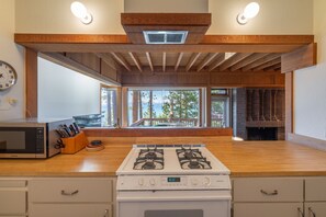 A kitchen with a gas stove, a microwave, and a window overlooking a deck. - Lakefront Northshore Townhome pano lake views, HOA private beach pool tennis (Tahoe City)