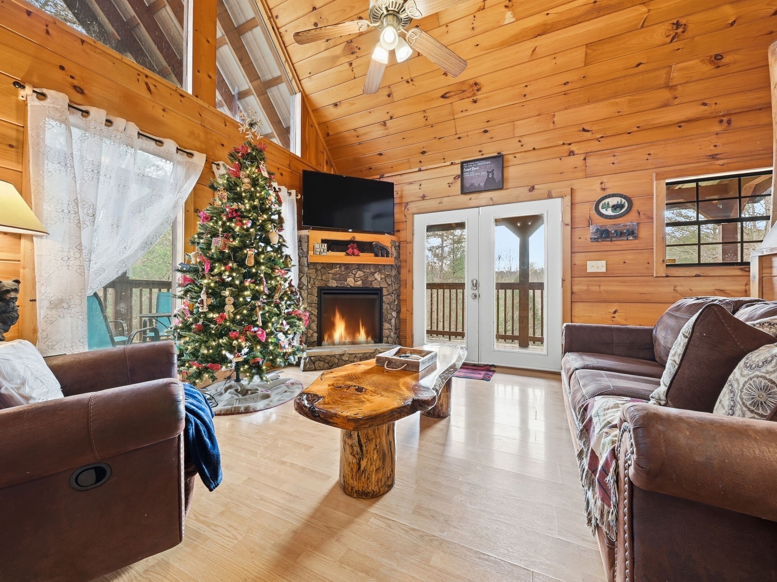 Interior acogedor de una cabaña con chimenea, sofás de cuero, una mesa de centro de madera y un árbol de Navidad.