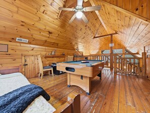 Een knus houten huisje met een pooltafel, een bed en een eethoek.