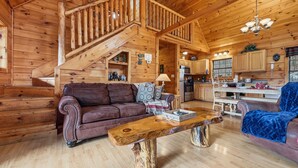L’intérieur d’une cabane en bois comprend un escalier, un salon avec un canapé et une table basse, ainsi qu’un coin cuisine.