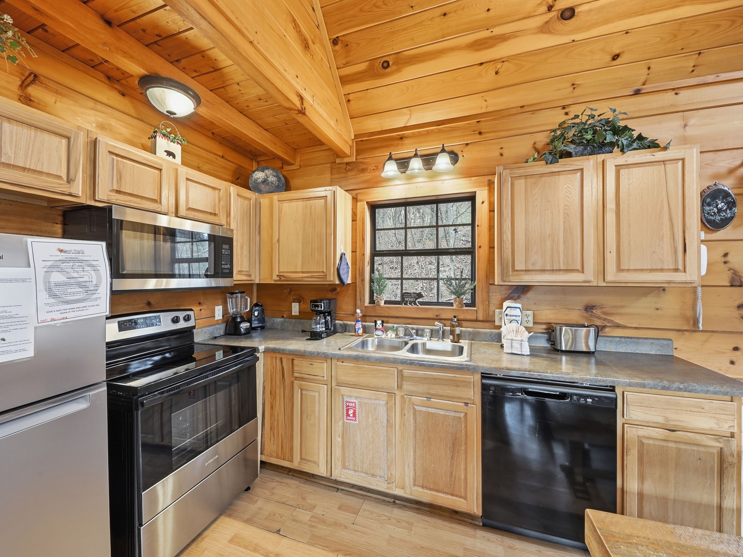 A kitchen with wooden cabinets, stainless steel appliances, a window, and a fire safety sign.