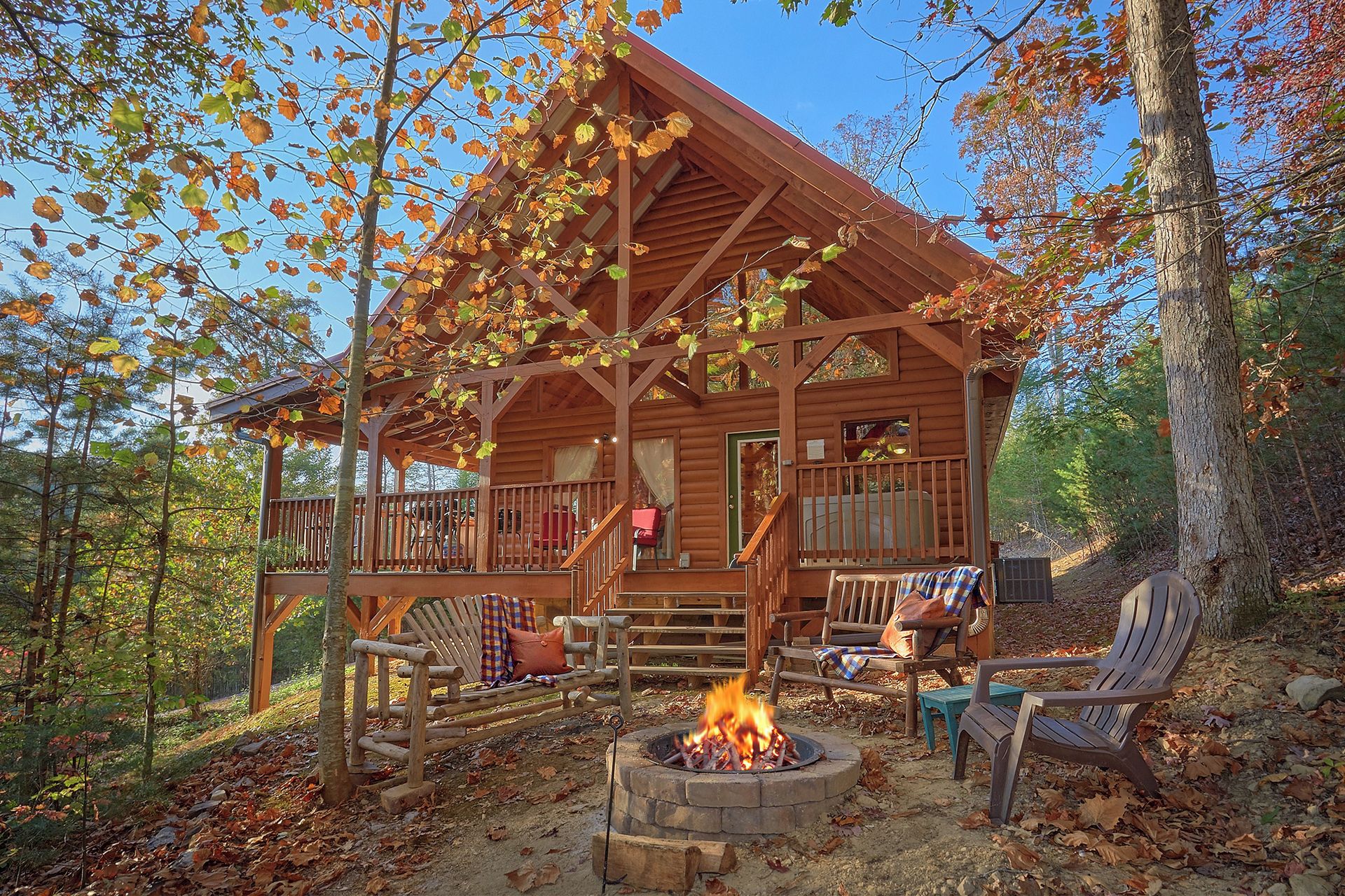 Une cabane en rondins avec un porche, un espace salon extérieur et un foyer.