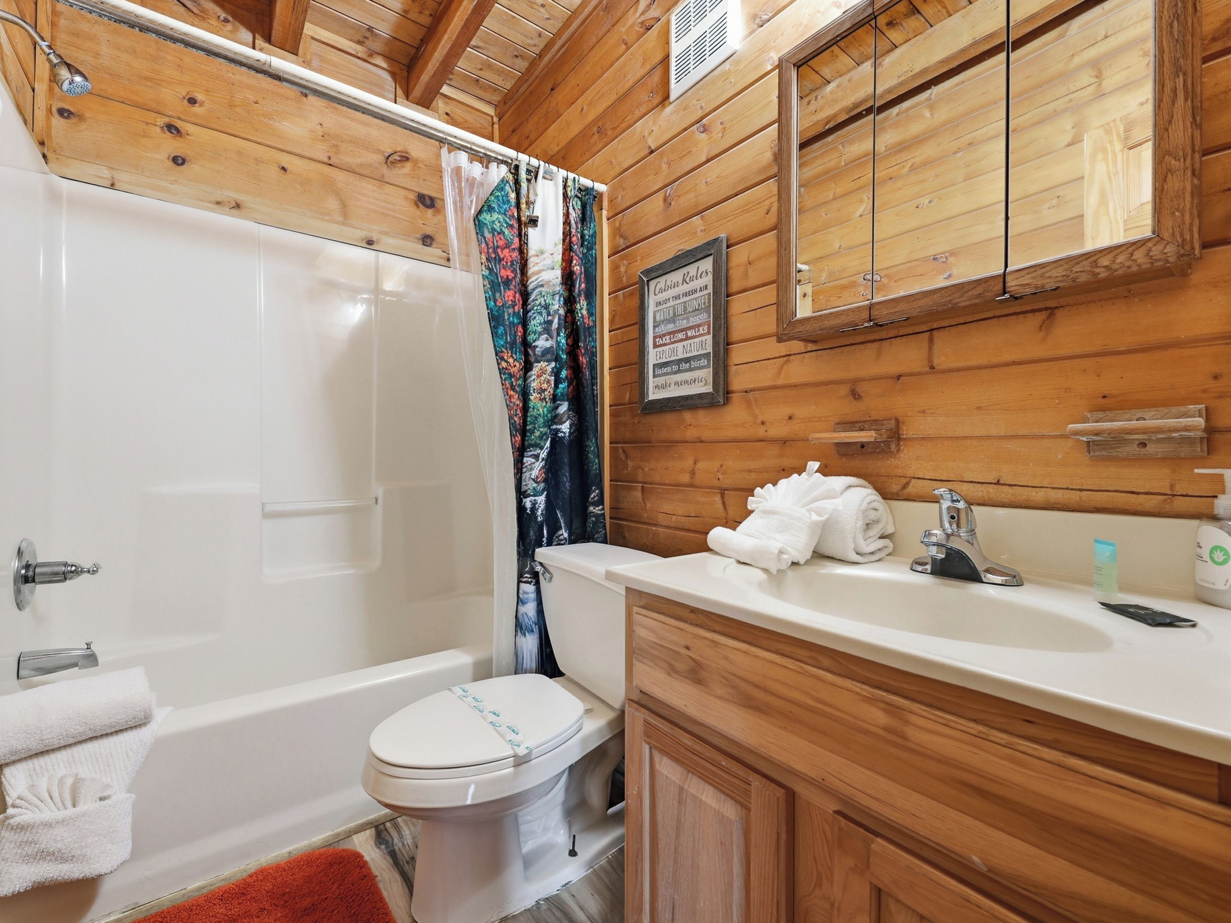 Ein Badezimmer einer Holzhütte mit Badewanne, Toilette und einem Holzanrichte mit Waschbecken.