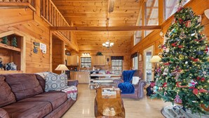 L’intérieur d’un chalet confortable, avec des murs en bois, un escalier en bois, un coin repas, un salon doté d’un canapé en cuir et un sapin de Noël décoré.