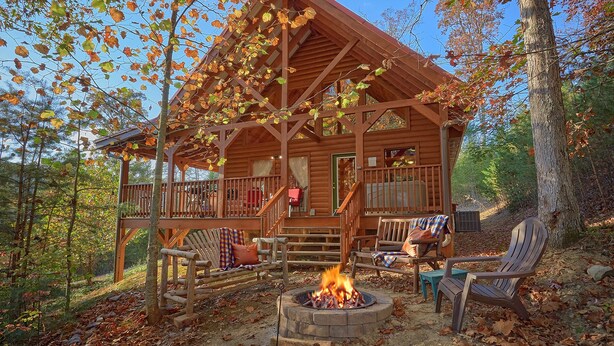 Une cabane en rondins avec un porche, un espace salon extérieur et un foyer.