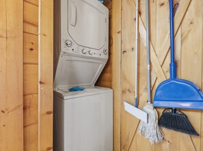 Een wasserij met een wasmachine, een dweil en een bezem.