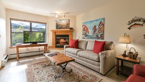 Una sala de estar con chimenea, un sofá, una mesa de centro y un televisor.