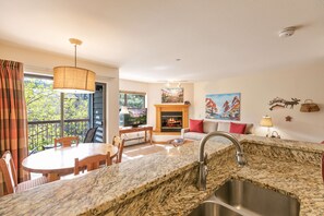 Una cocina con encimera de granito, un lavamanos y una zona de comedor con mesa y sillas.