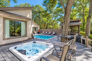 A pool area with a hot tub, lounge chairs, and a deck.